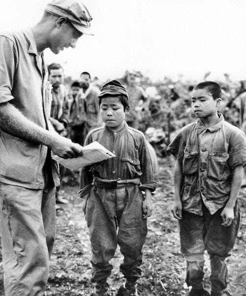 an american soldier speaks with two young Japanese boys, who look unhappy